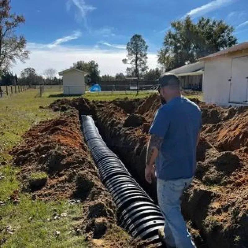 A man is standing next to a large pipe in the dirt.