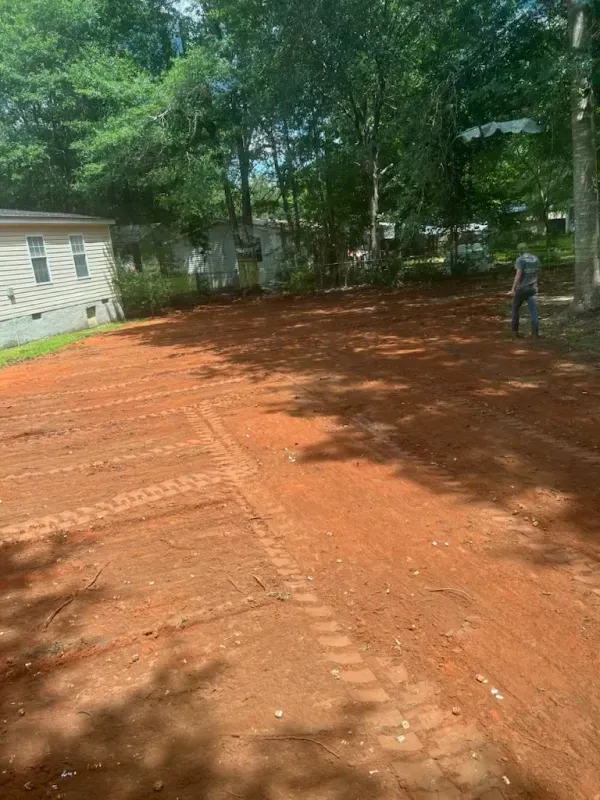 A man is standing in the middle of a dirt field.