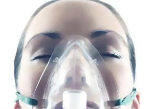 Mujer con los ojos cerrados usando una máscara de oxígeno.