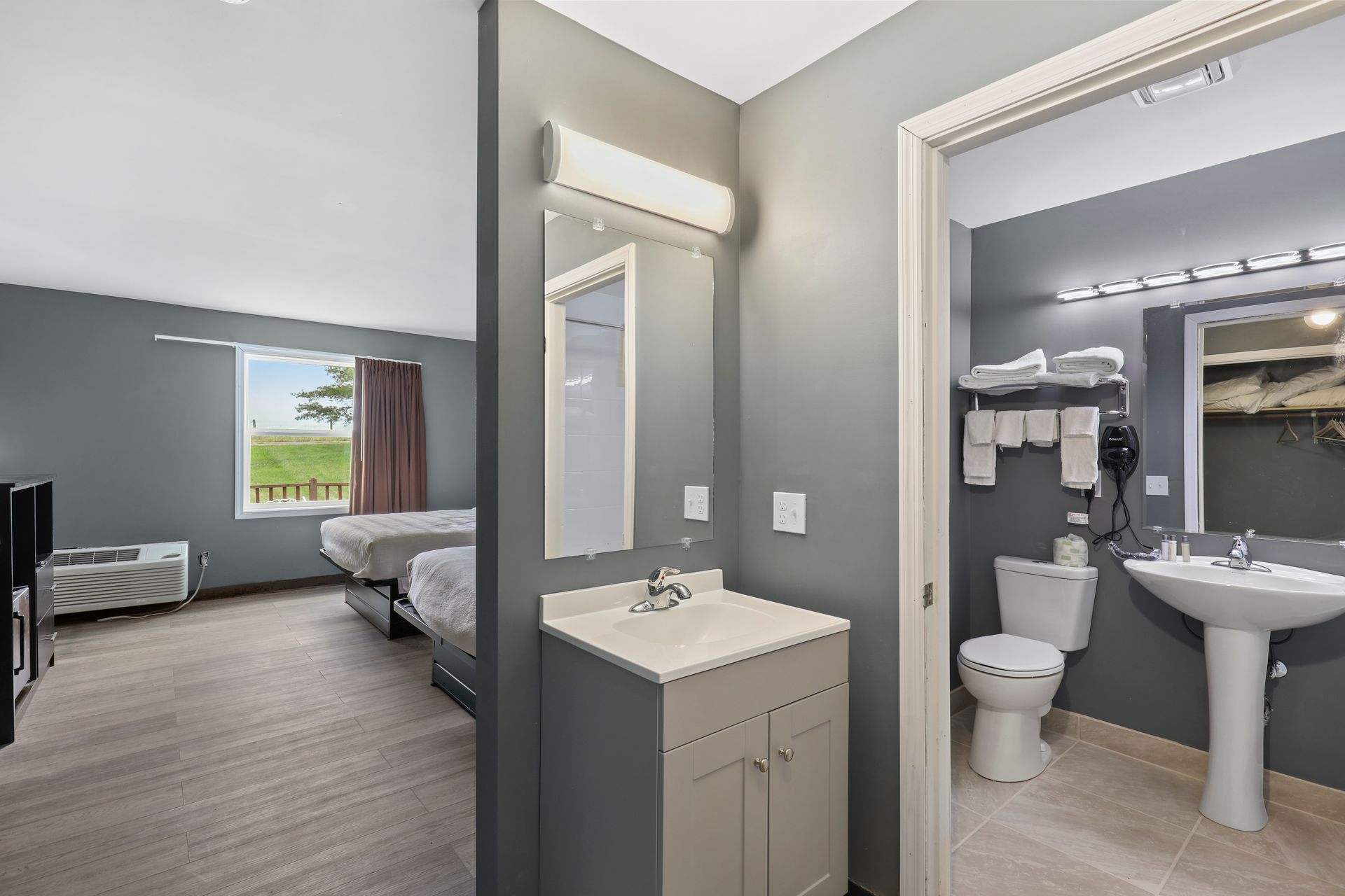 A hotel room with a sink , toilet , and mirror.