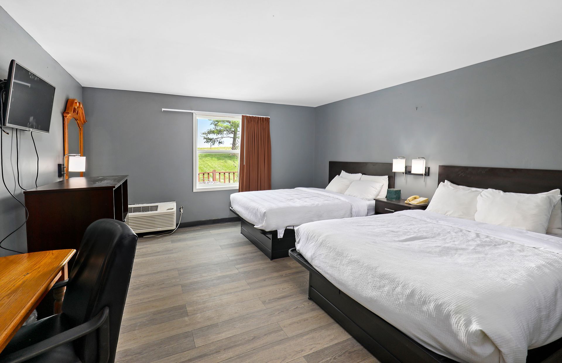 A hotel room with two beds , a desk and a television.