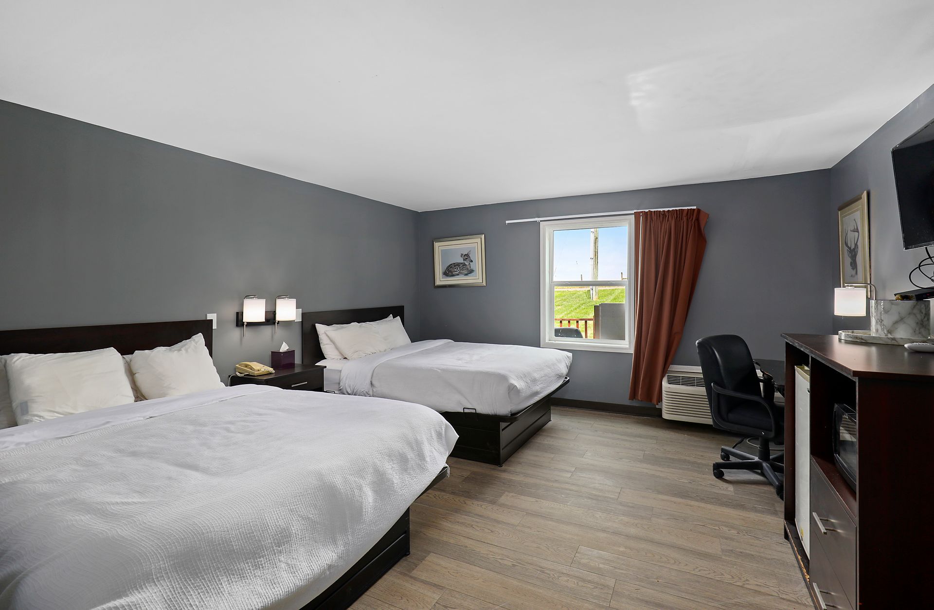 A hotel room with two beds , a desk , and a window.