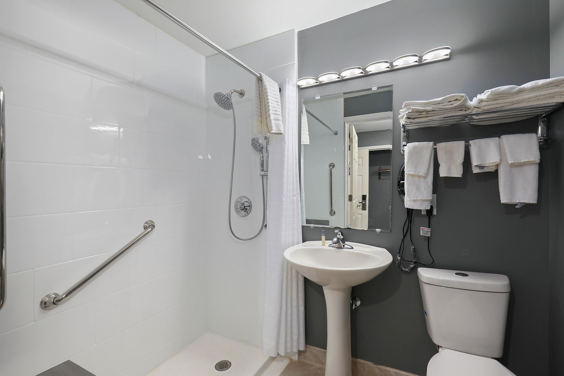 A bathroom with a sink , toilet , shower and mirror.