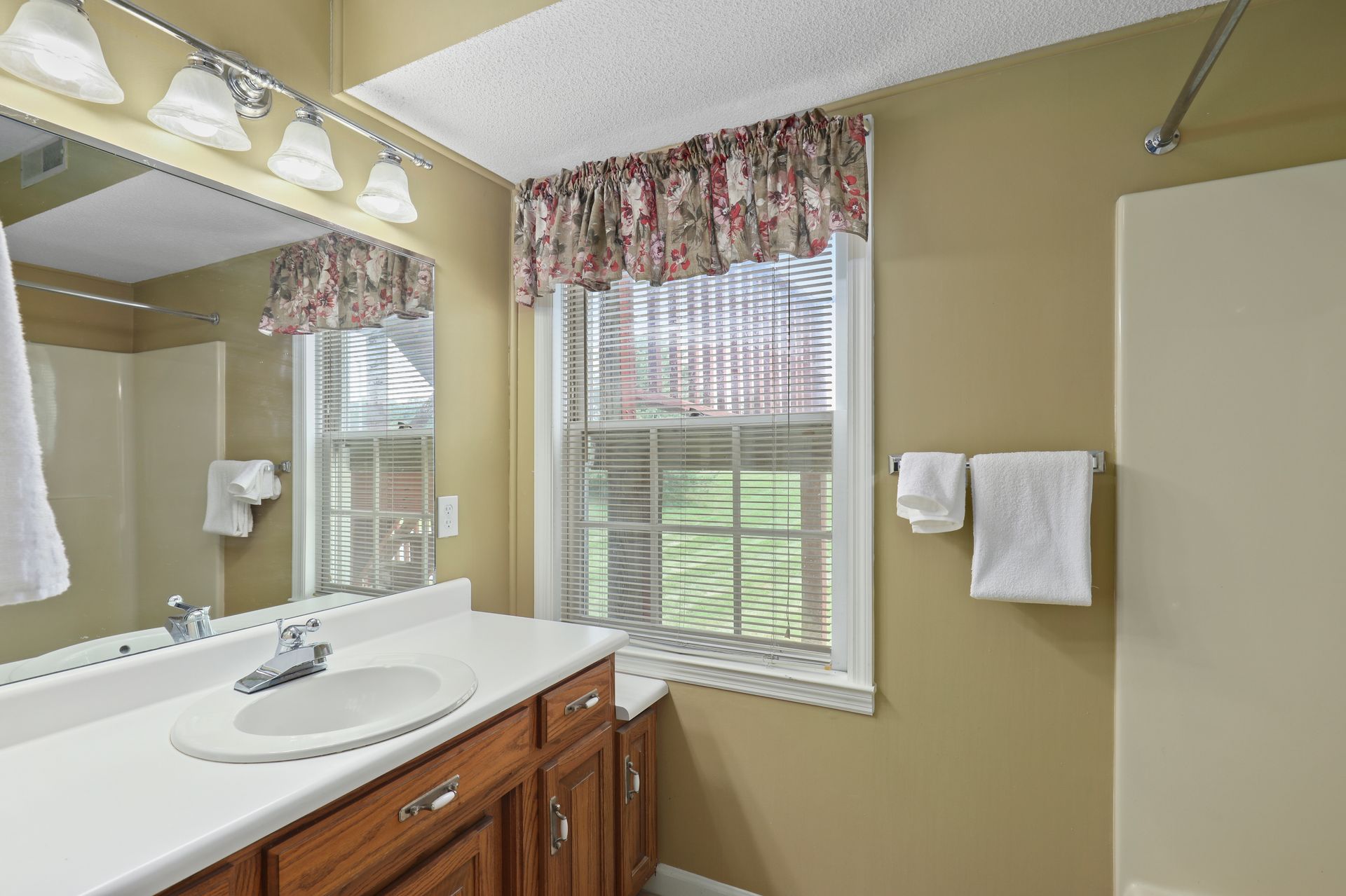 A bathroom with a sink , mirror and window.