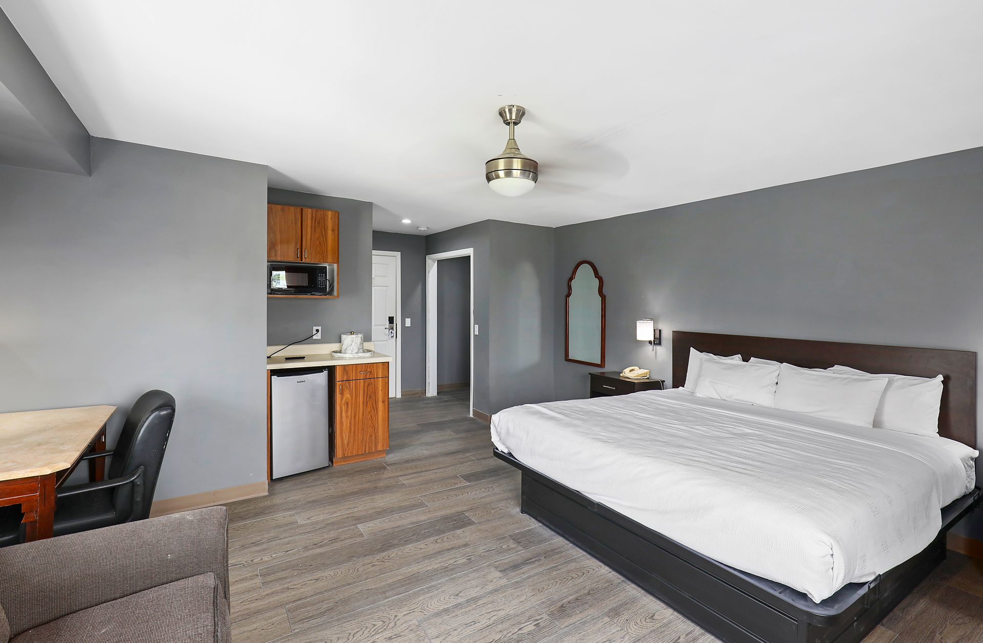 A hotel room with a king size bed , a chair , a desk , and a kitchen.