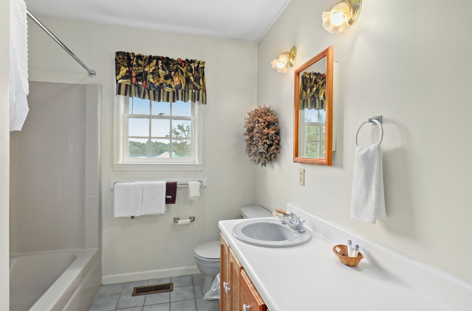 A bathroom with a sink , toilet , shower and window