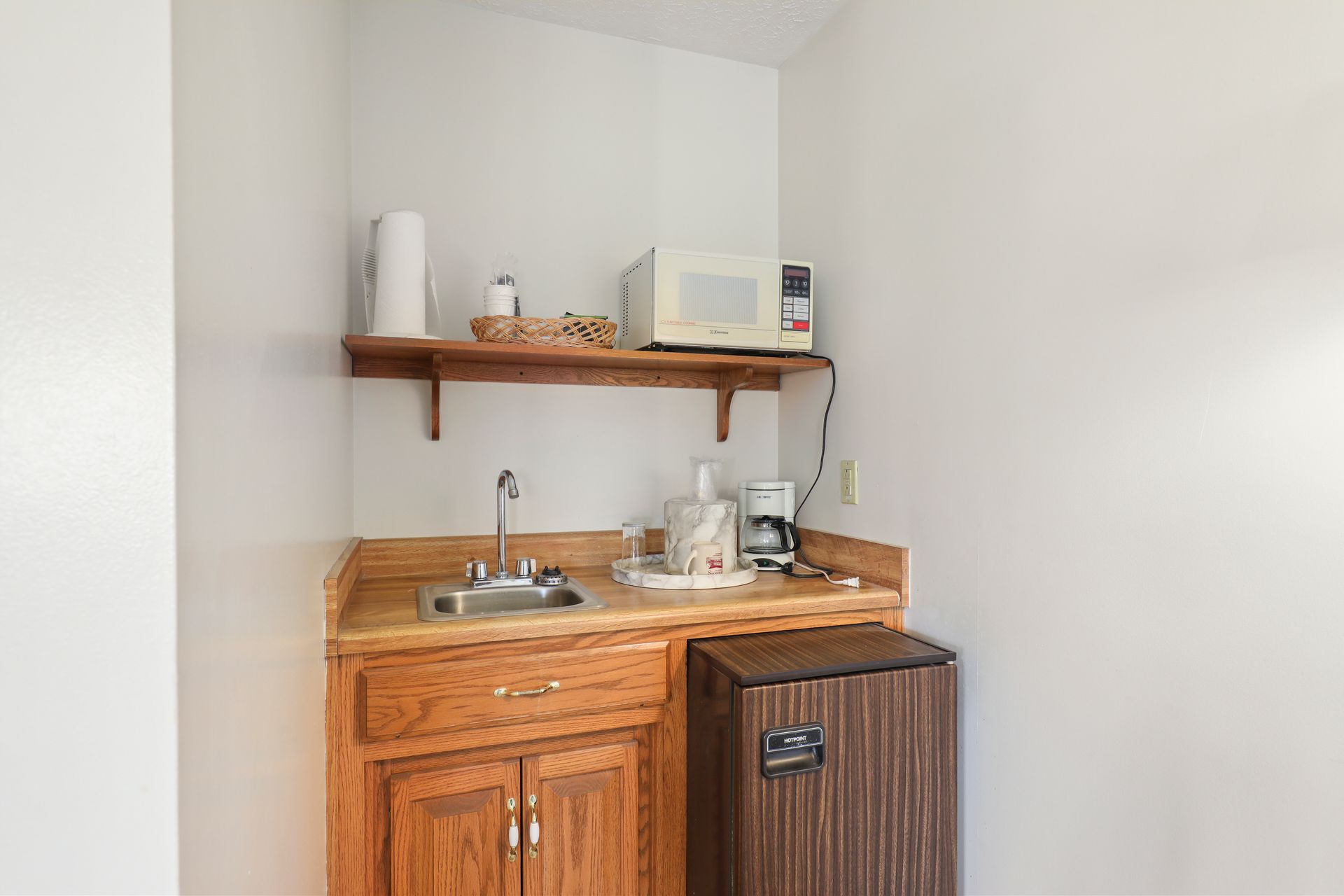 A small kitchen with a sink , microwave , coffee maker and refrigerator.