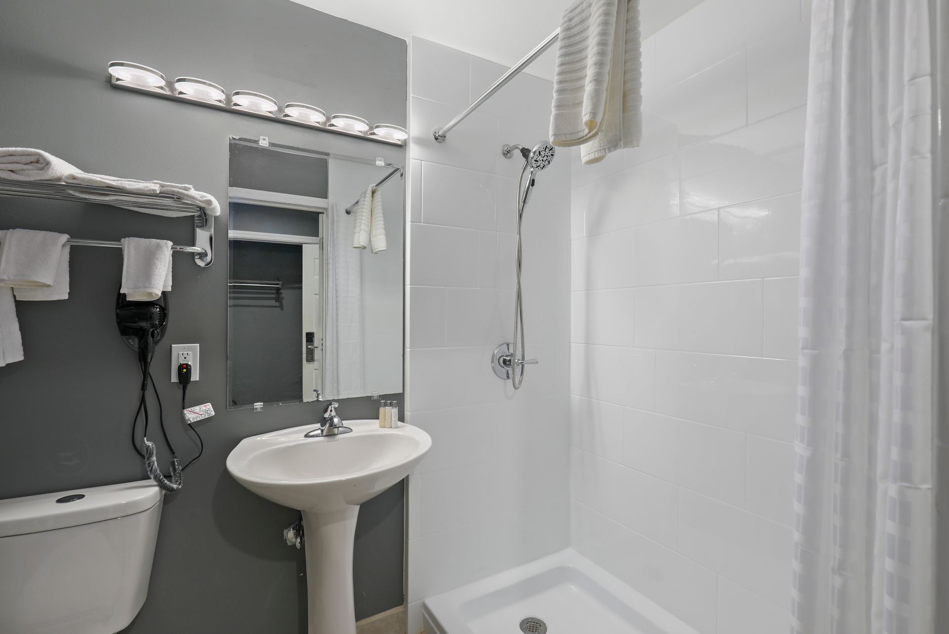 A bathroom with a sink , toilet , shower and mirror.