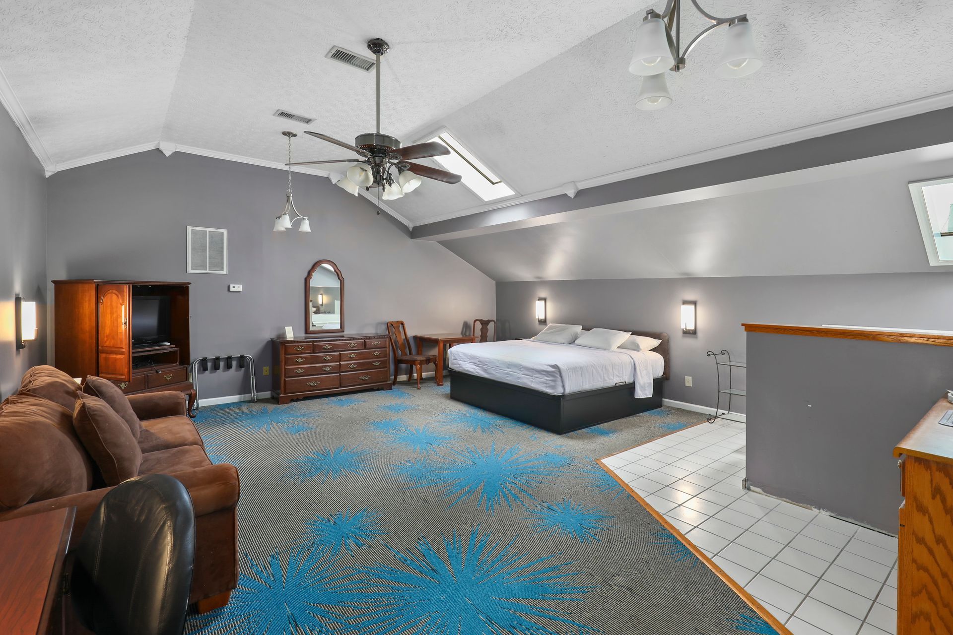 A hotel room with a king size bed , a couch , and a ceiling fan.