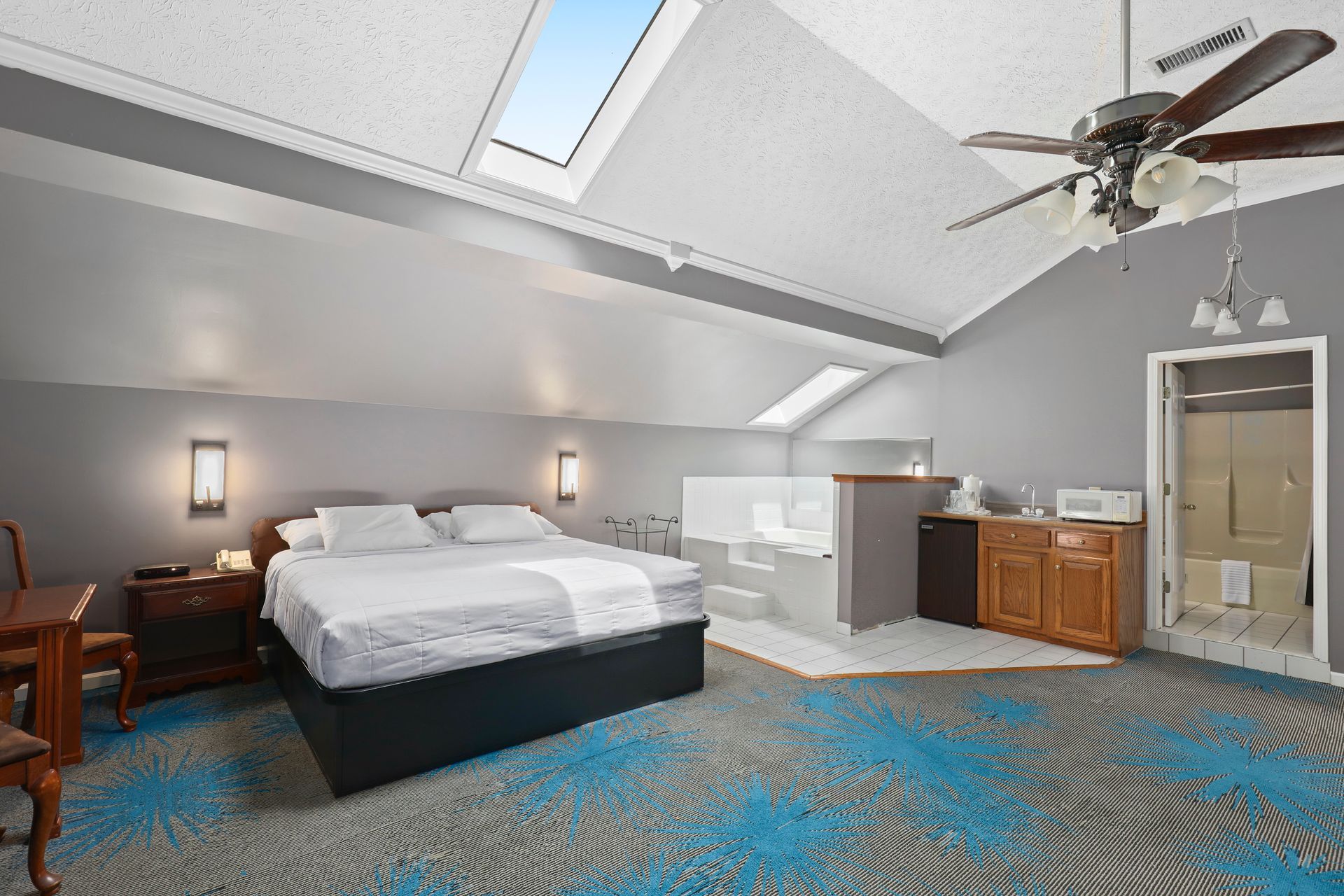 A bedroom with a king size bed , a ceiling fan and a jacuzzi tub.