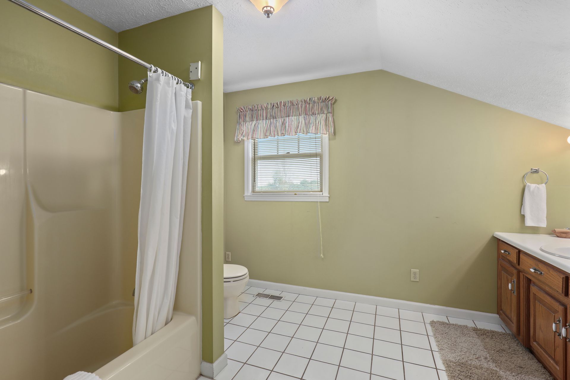 A bathroom with a tub , toilet and window