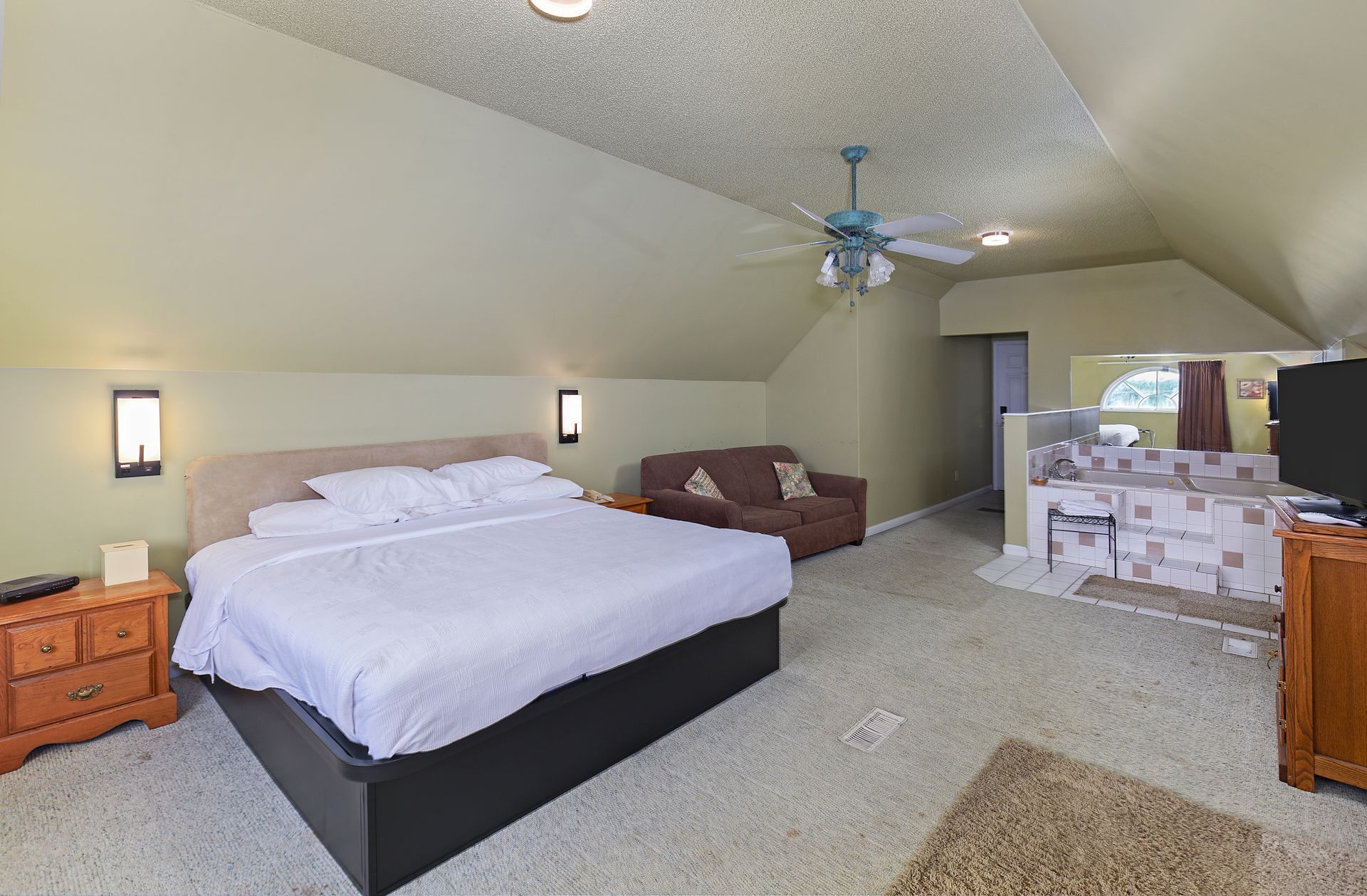 A bedroom with a king size bed and a ceiling fan
