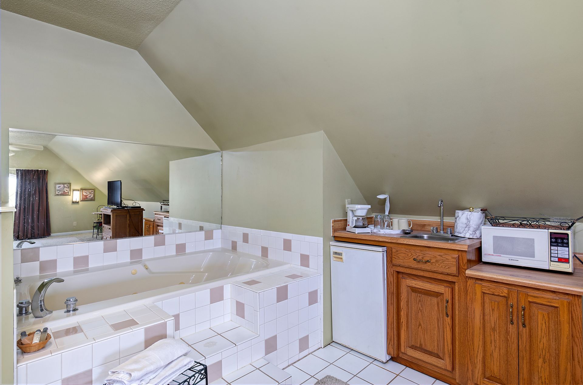 A bathroom with a jacuzzi tub , sink , and microwave.