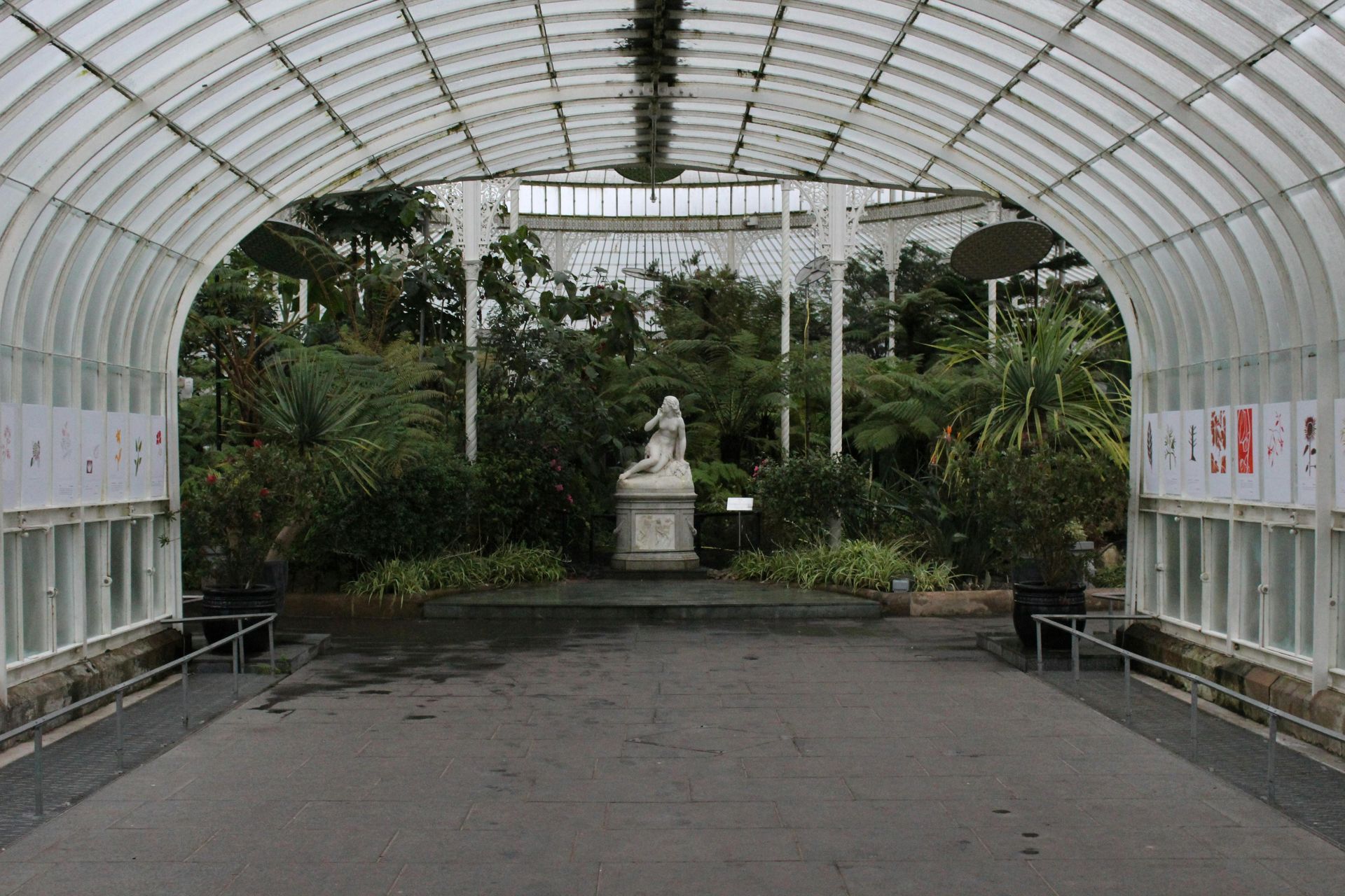 There is a statue in the middle of a greenhouse.