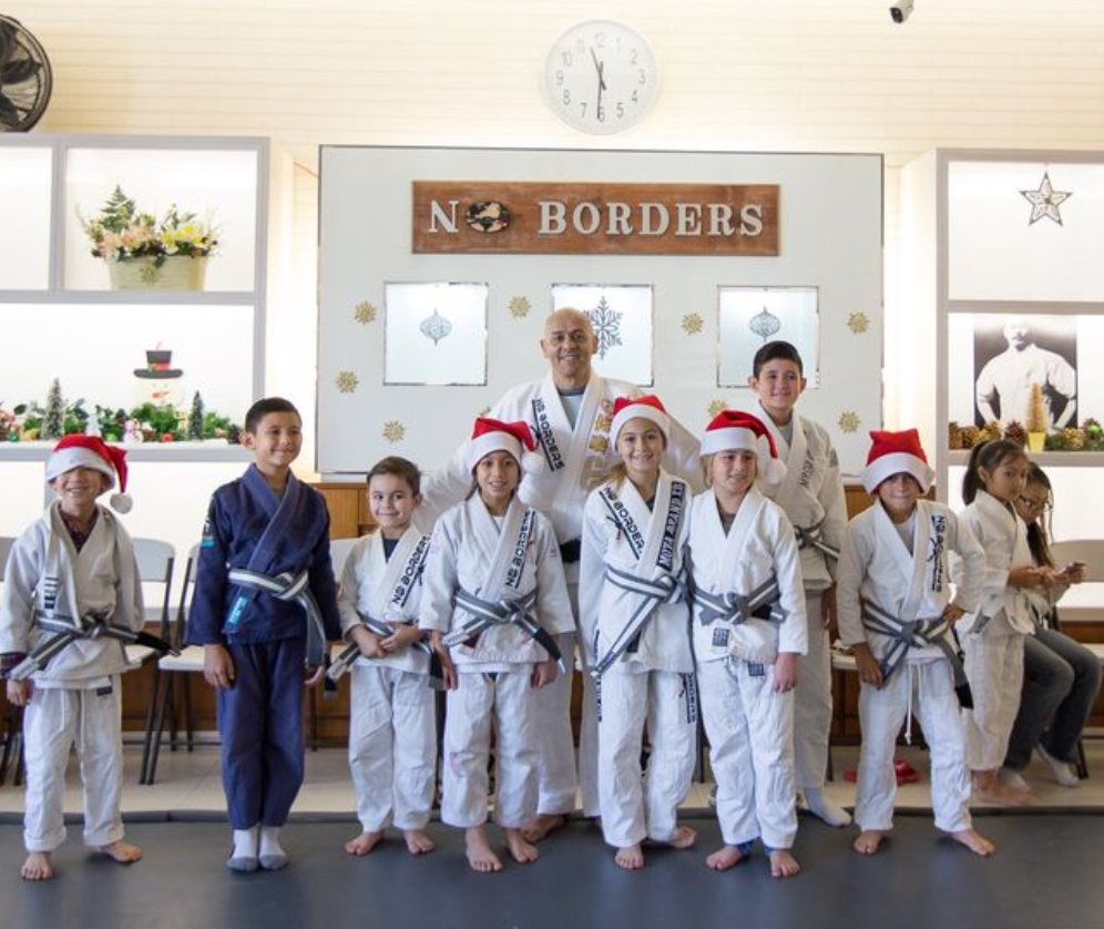 Kids in Santa hats and gis with instructor at a martial arts studio that says 