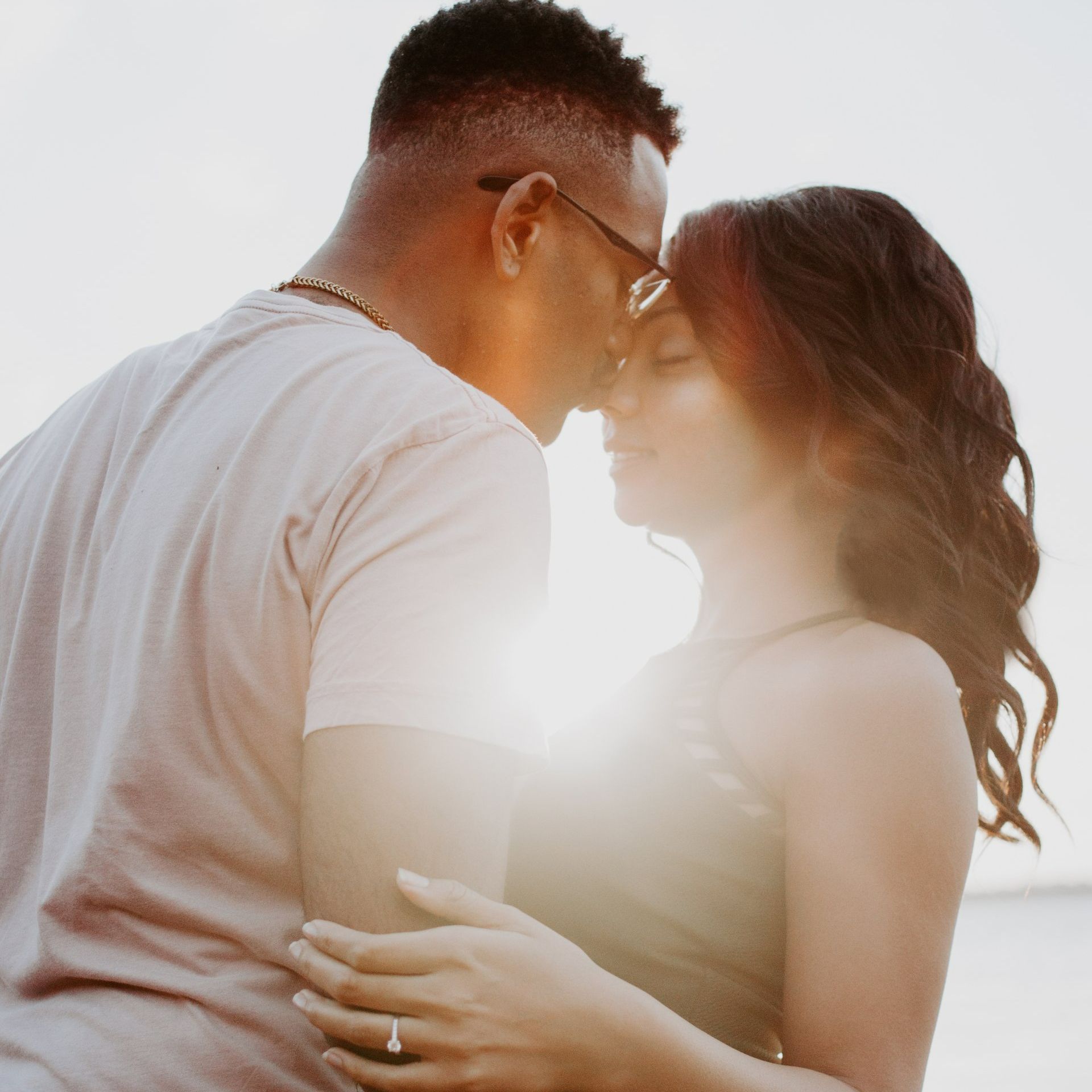 A man and a woman are kissing on the beach.