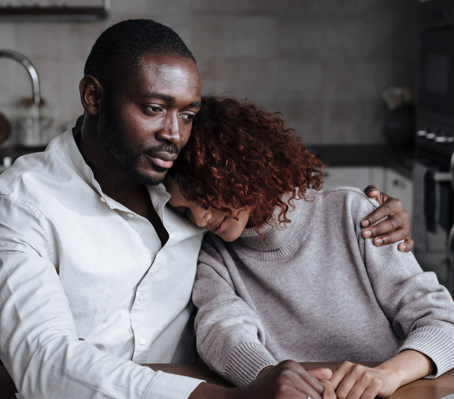 A man and a woman are sitting at a table holding hands.