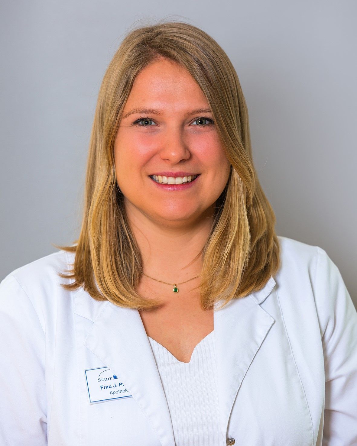 Eine Frau, die einen weißen Laborkittel mit dem Buchstaben E darauf trägt