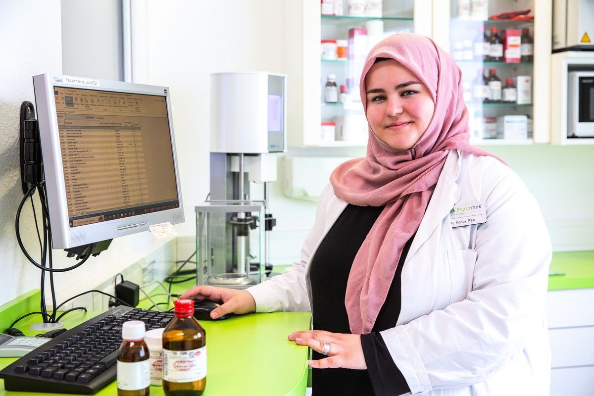 Eine Frau mit Hijab steht in einem Labor vor einem Computer.