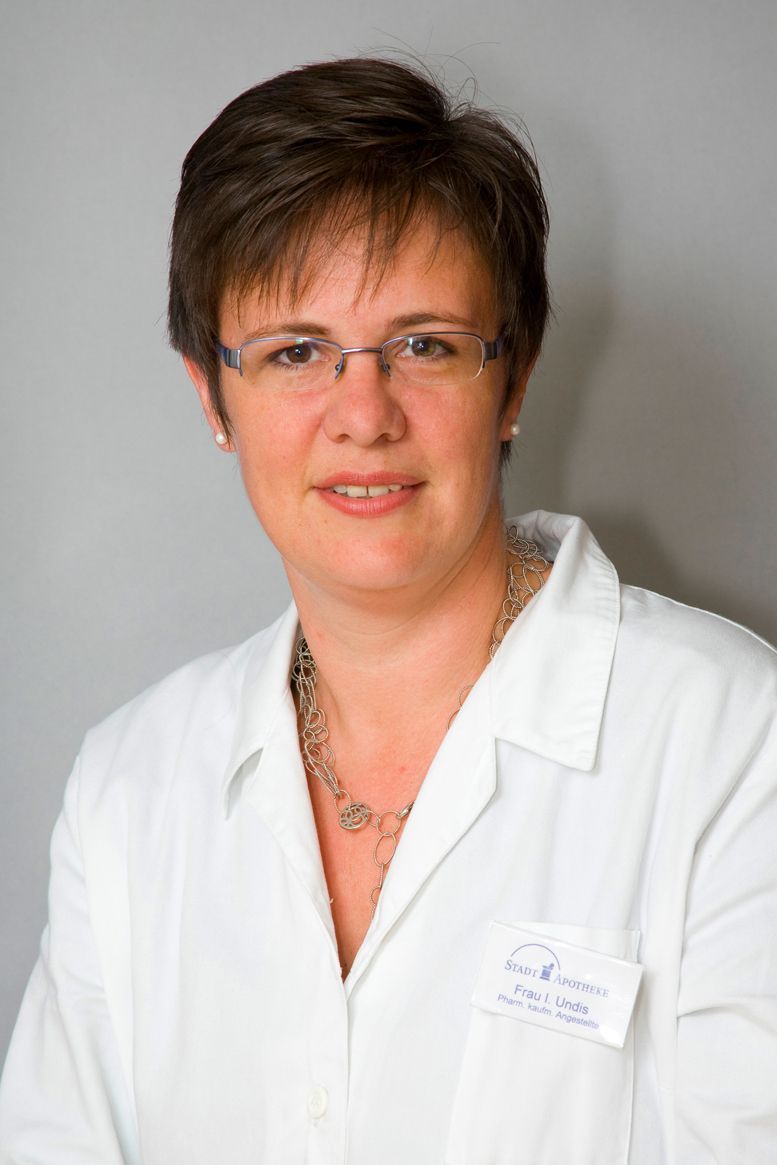 Eine Frau mit Brille und weißem Laborkittel lächelt in die Kamera.