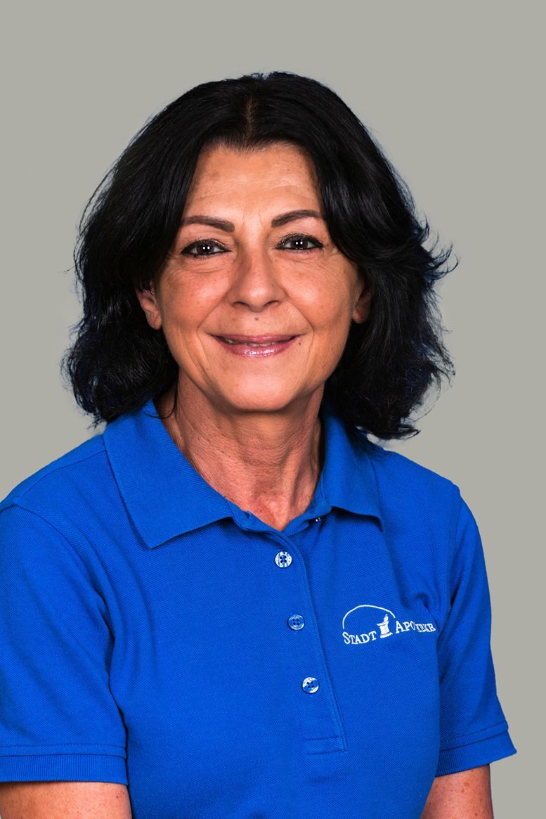 Eine Frau in einem blauen Poloshirt lächelt in die Kamera.