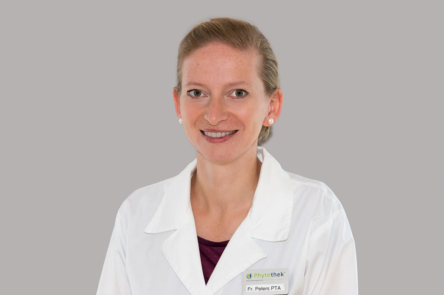 Eine Frau in einem weißen Laborkittel lächelt in die Kamera.