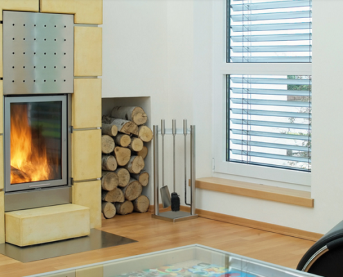Fireplace with burning fire, wood storage, and window in a modern living room.