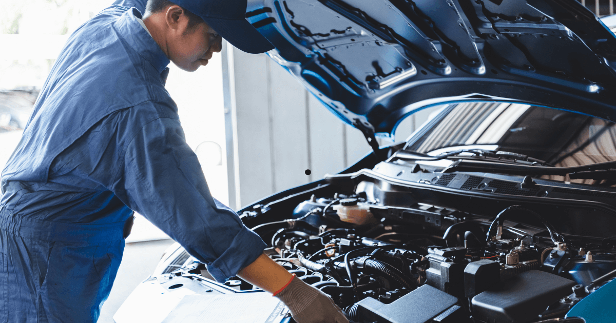 a mechanic inspecting under the hood of a car