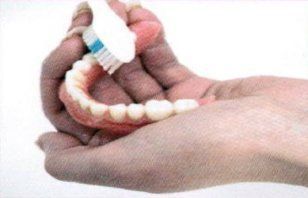 A person is brushing the denture