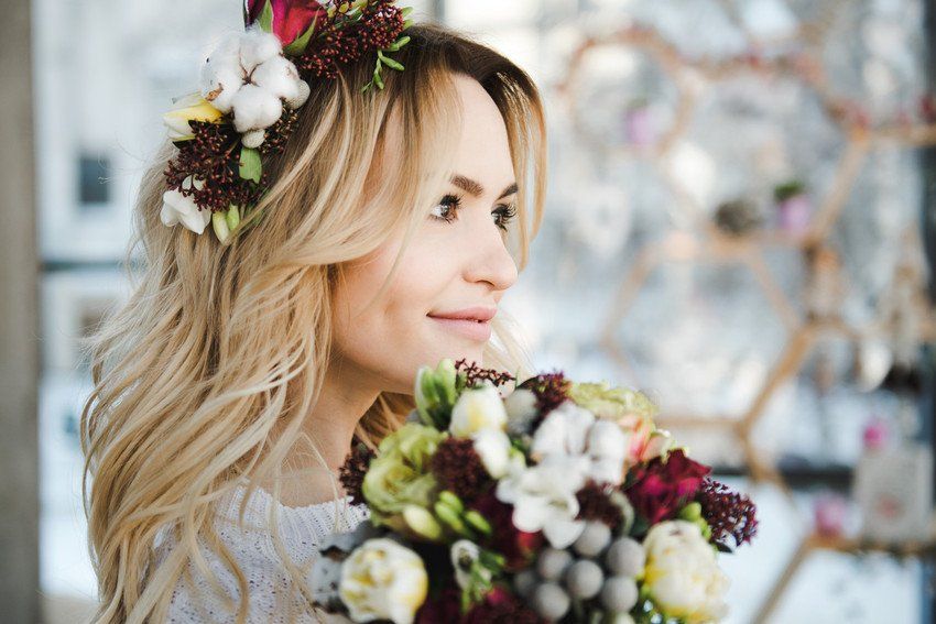 Portrait of Beautiful young bride in white wedding knitted dress with nice bouquet of flowers
