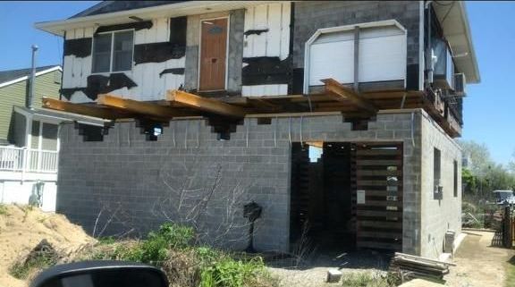 A car is parked in front of a house that is being demolished