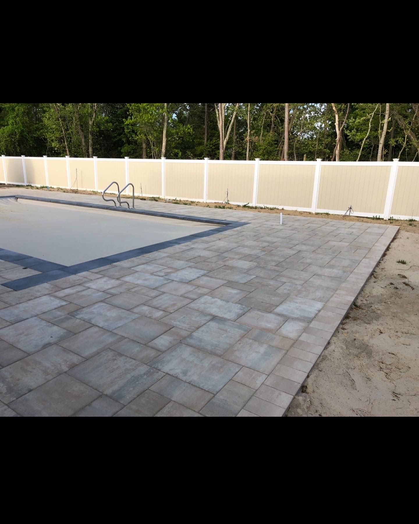 A large swimming pool with a white fence surrounding it.