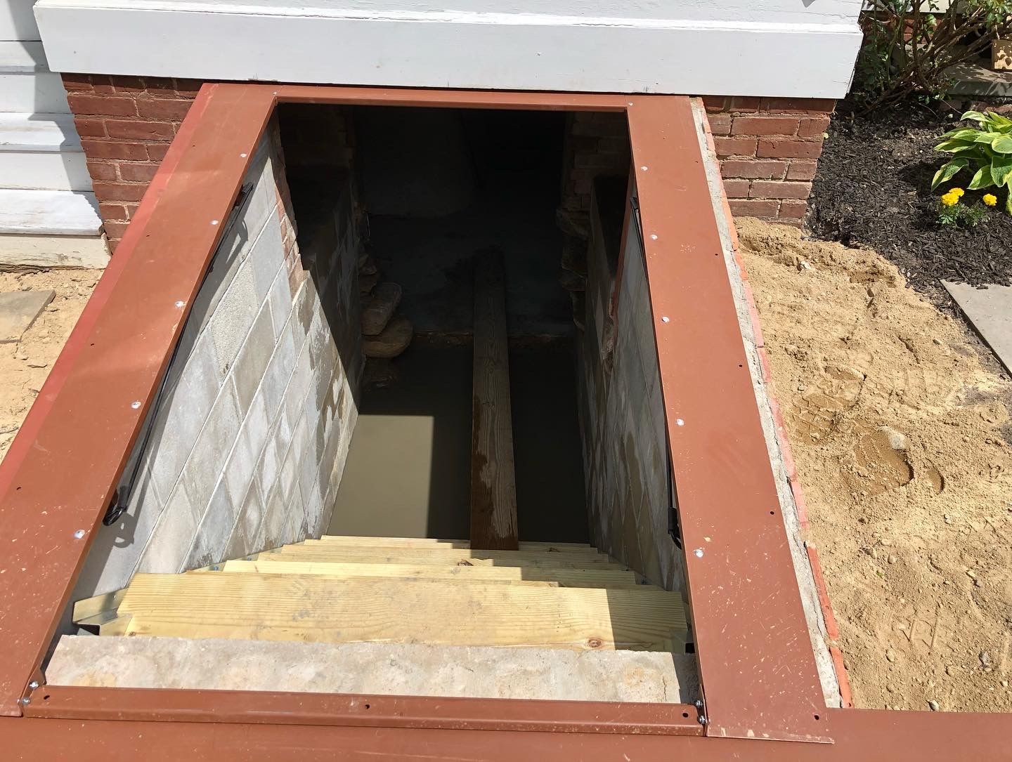 A staircase leading up to a basement under a brick building.