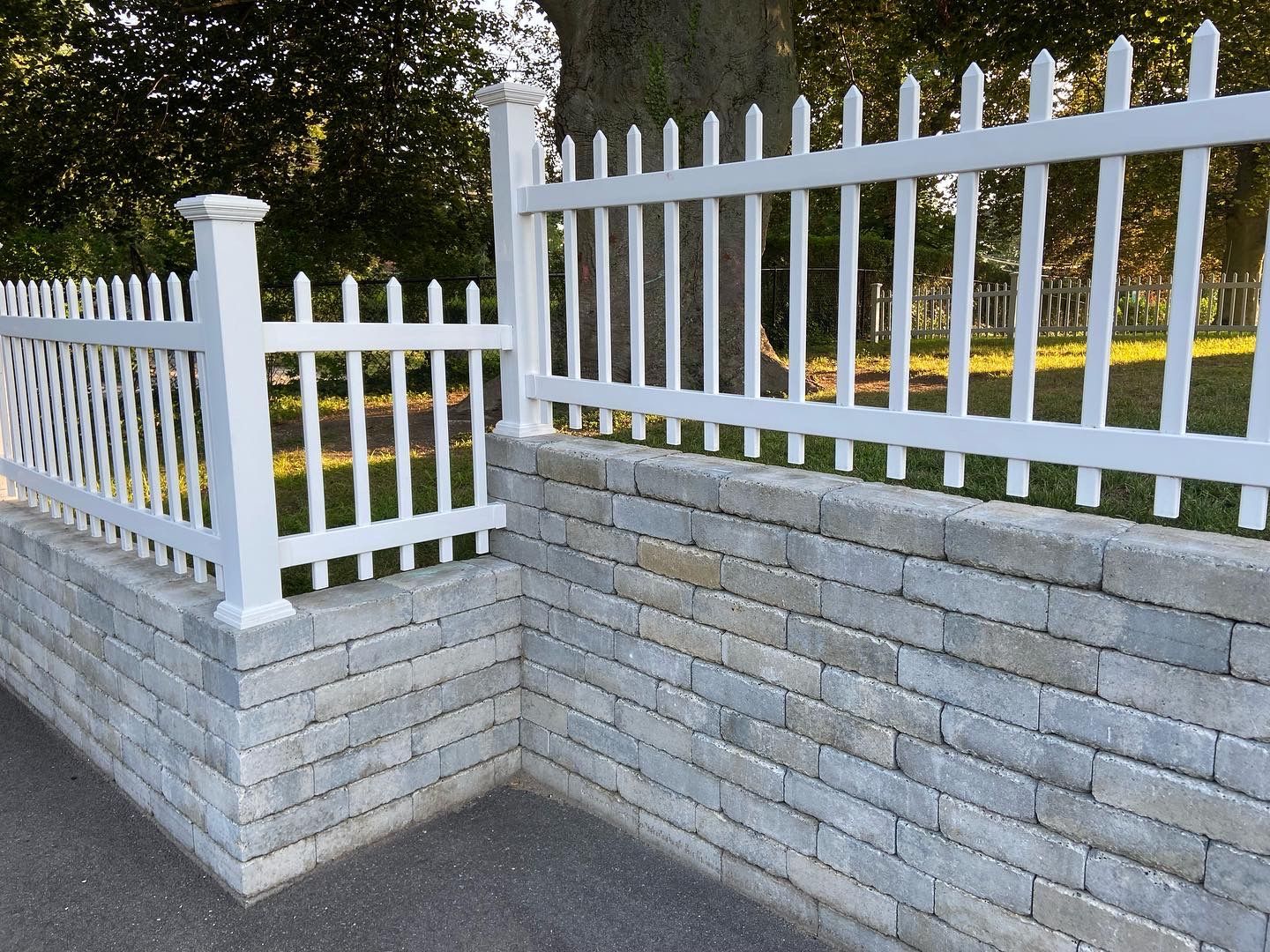 A white picket fence surrounds a brick wall