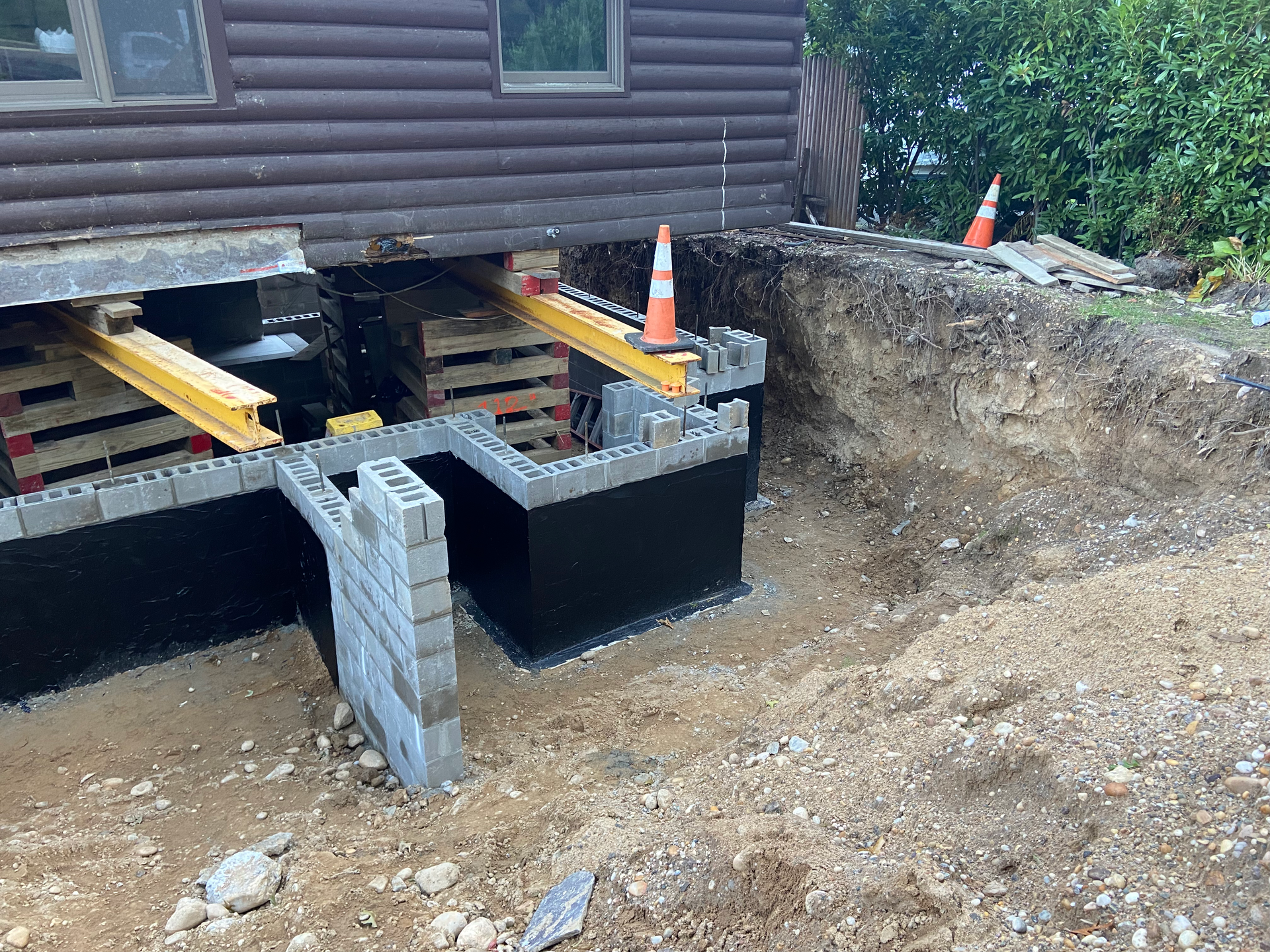A log cabin is being built on top of a dirt hill.