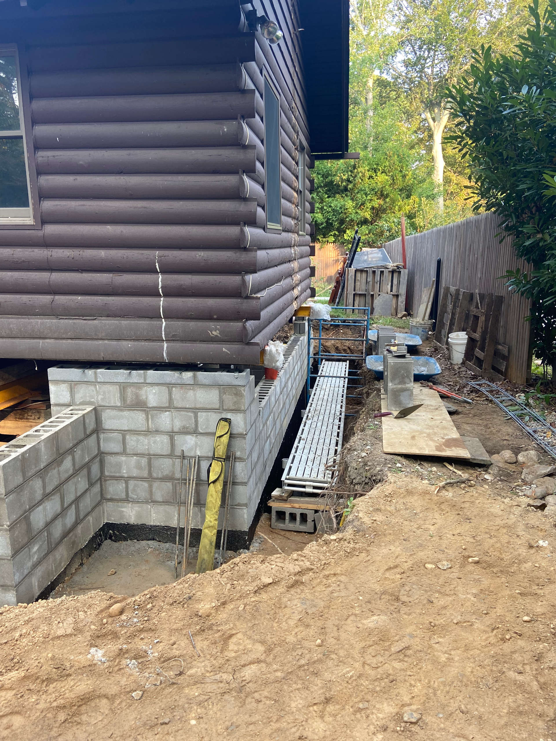 A log cabin is being built on a foundation with bricks.