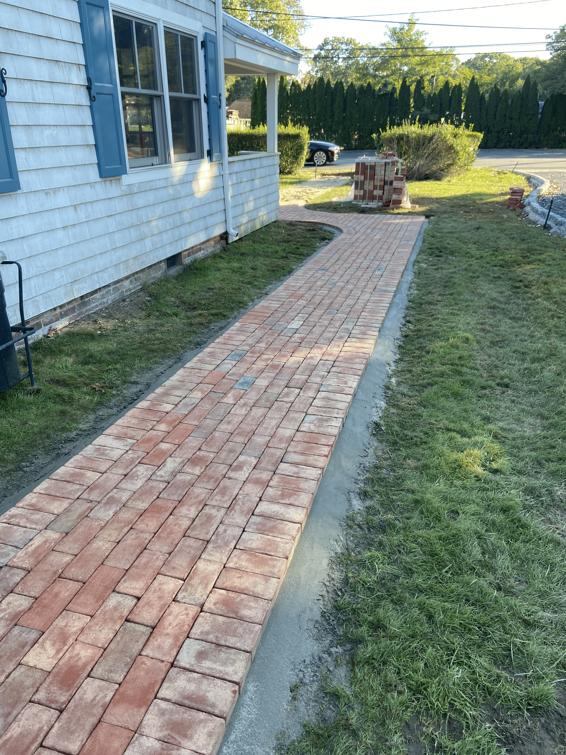 A brick walkway is being built in front of a house.