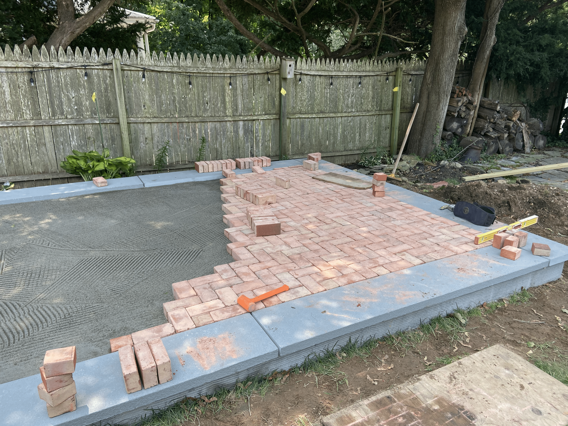 A brick walkway is being built in a backyard.