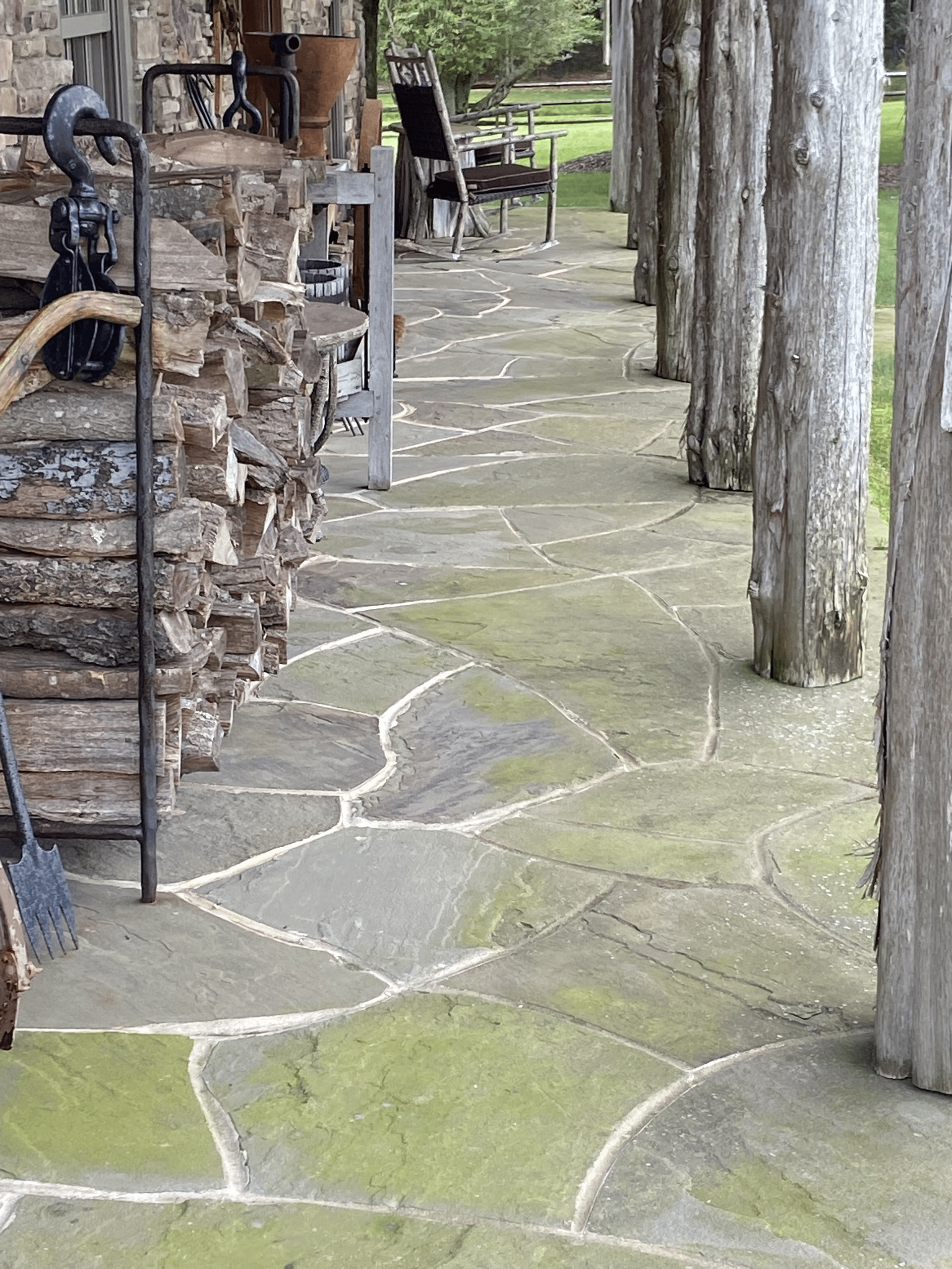 A stone walkway with a stack of logs in the background