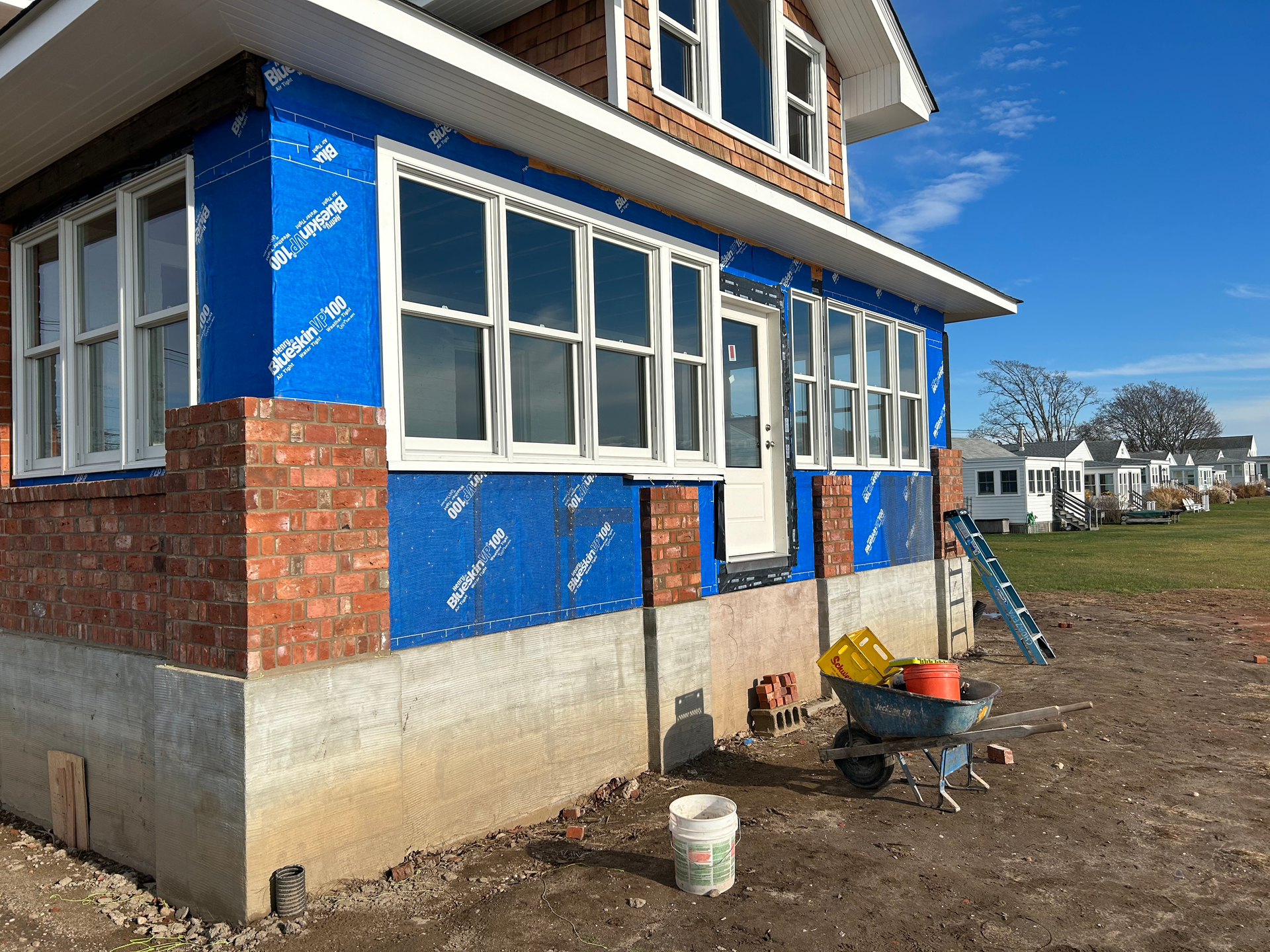 A house is being built with a wheelbarrow in front of it.
