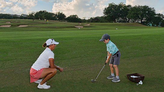 Person teaching a child to golf as spanish oaks golf club