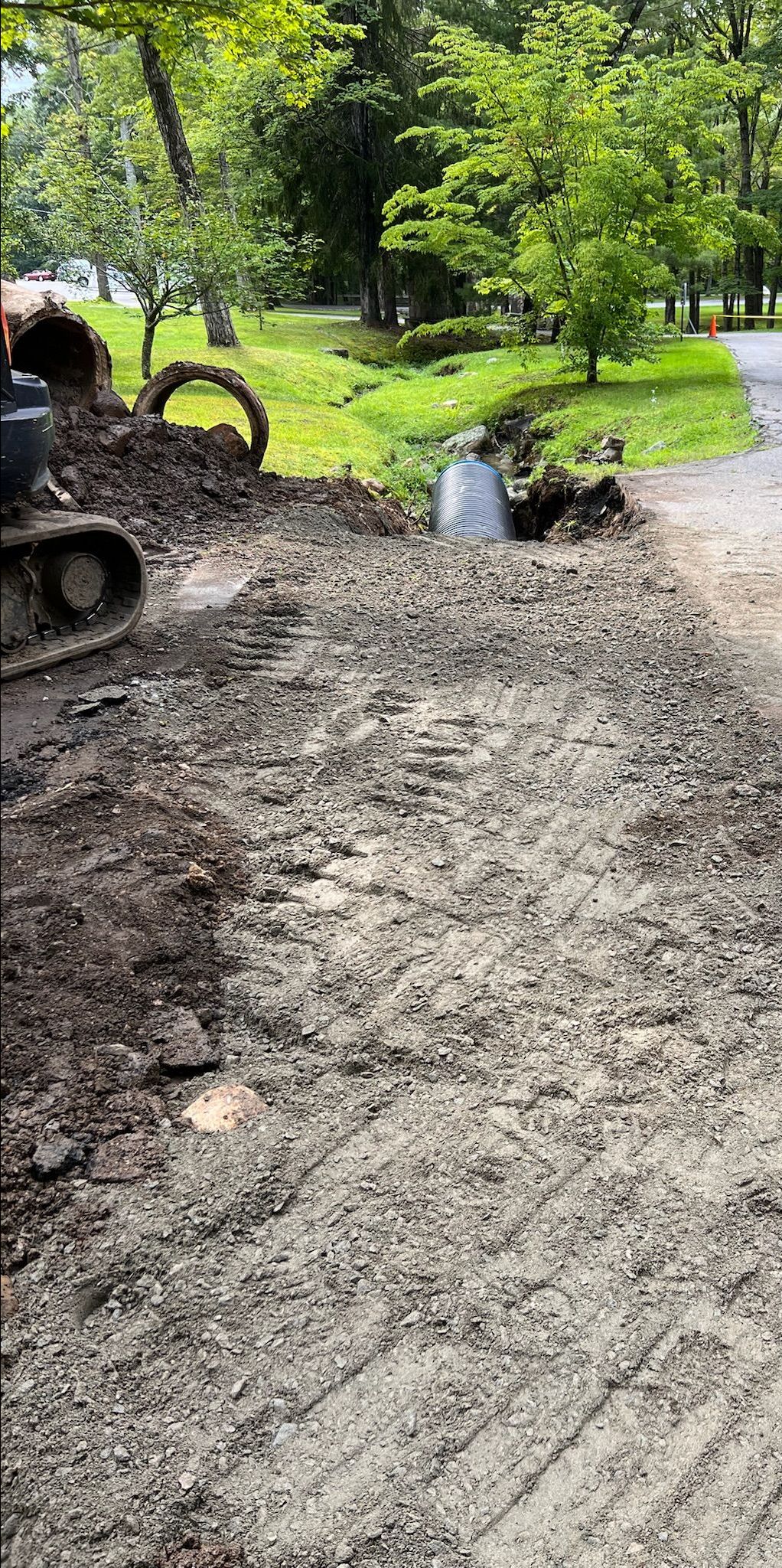 A truck is driving down a dirt road next to a bulldozer.