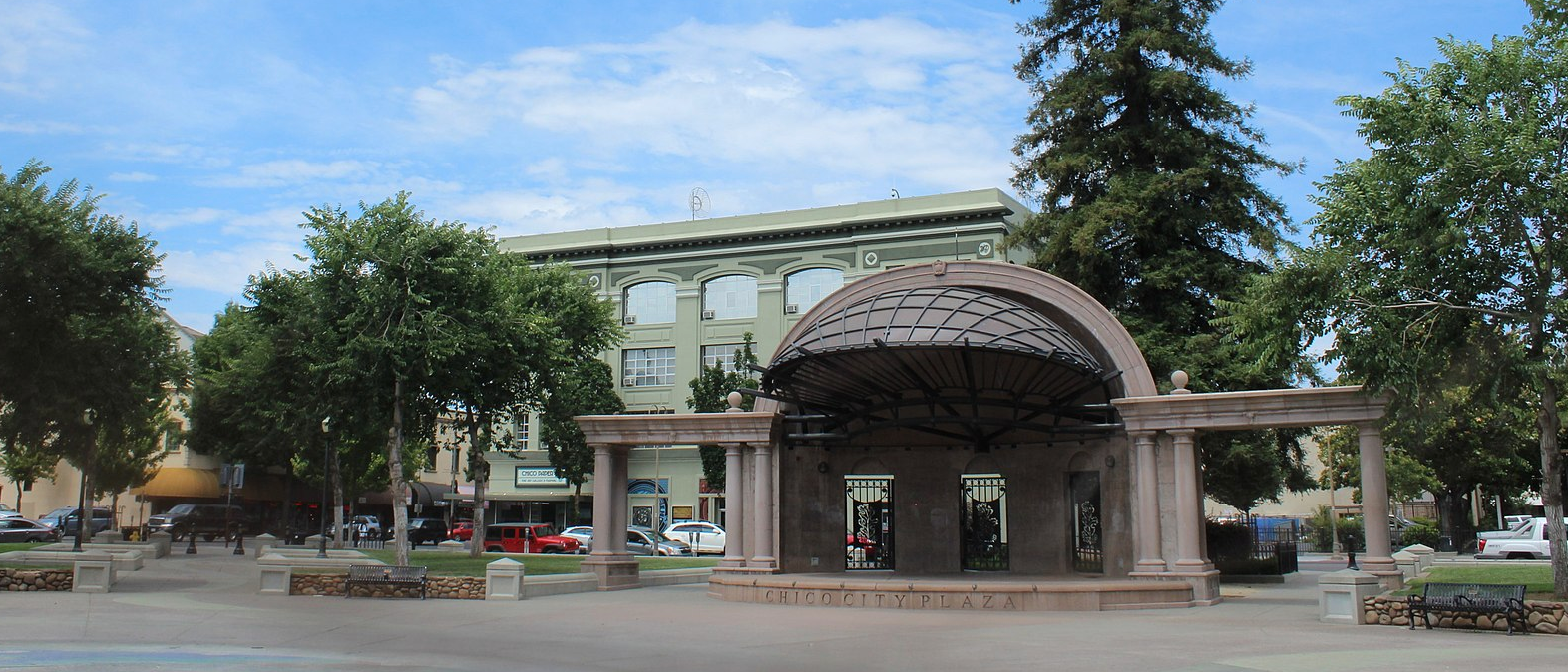 A gazebo in a city square surrounded by trees and buildings
