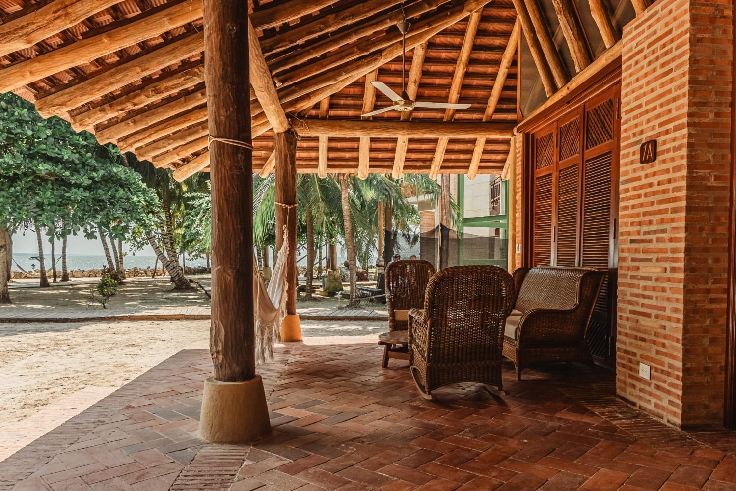 Covered porch with chairs, brick wall, and view of trees and water.