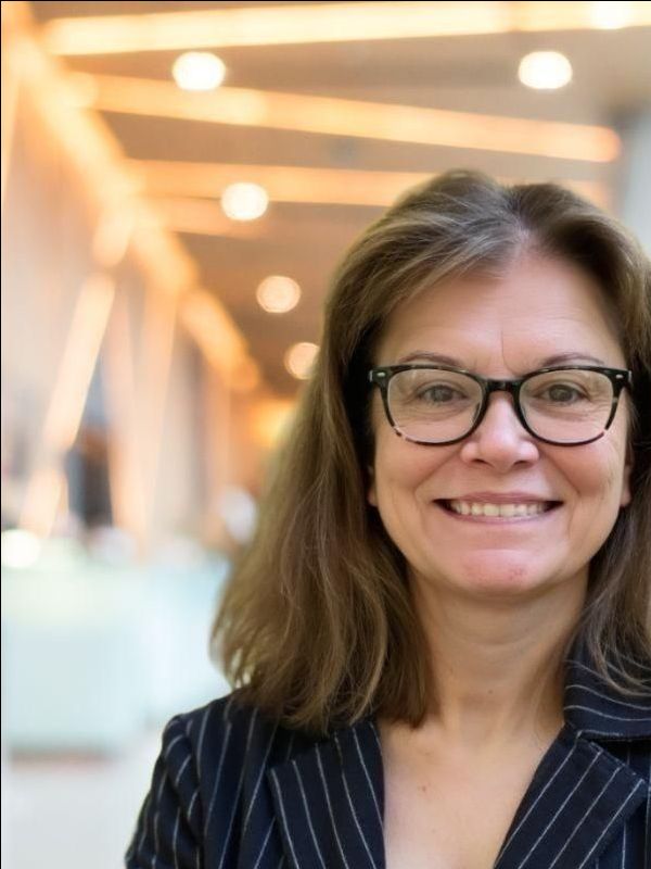 A woman wearing glasses and a striped jacket is smiling for the camera.