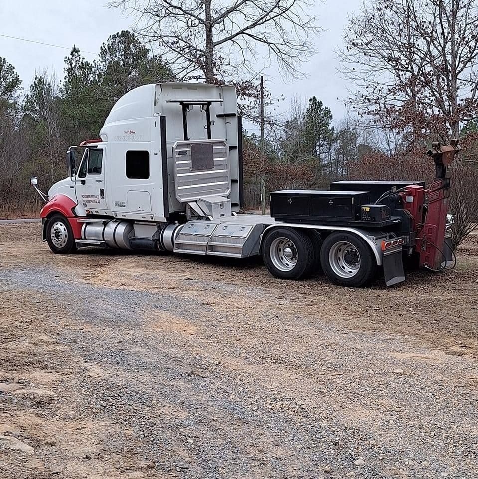 A semi truck is parked in a gravel lot.