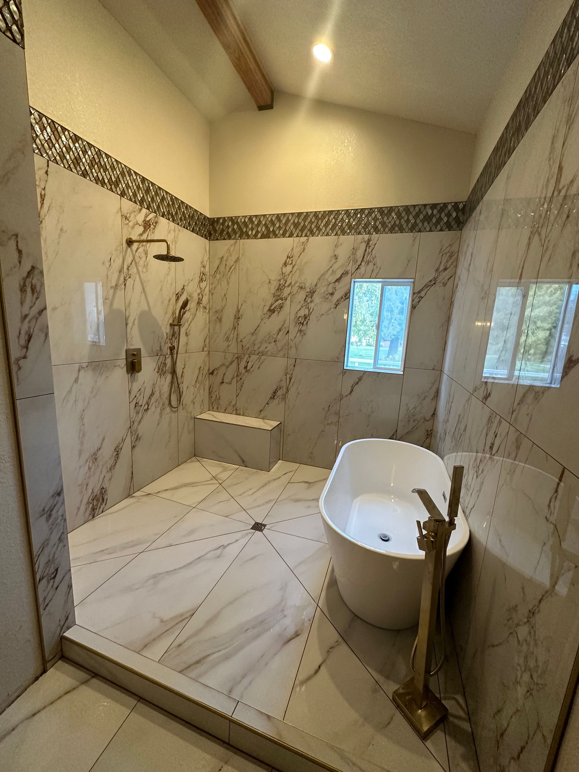 Bathroom with marble-like walls, a shower, a freestanding tub, and a small window.