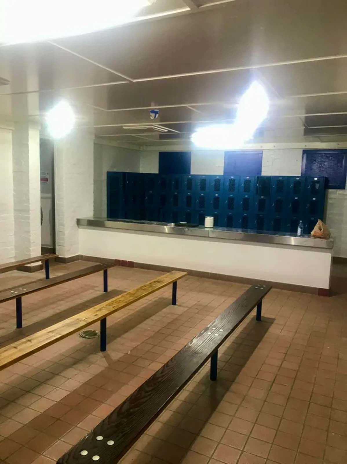 A row of benches in a room with lockers in the background.