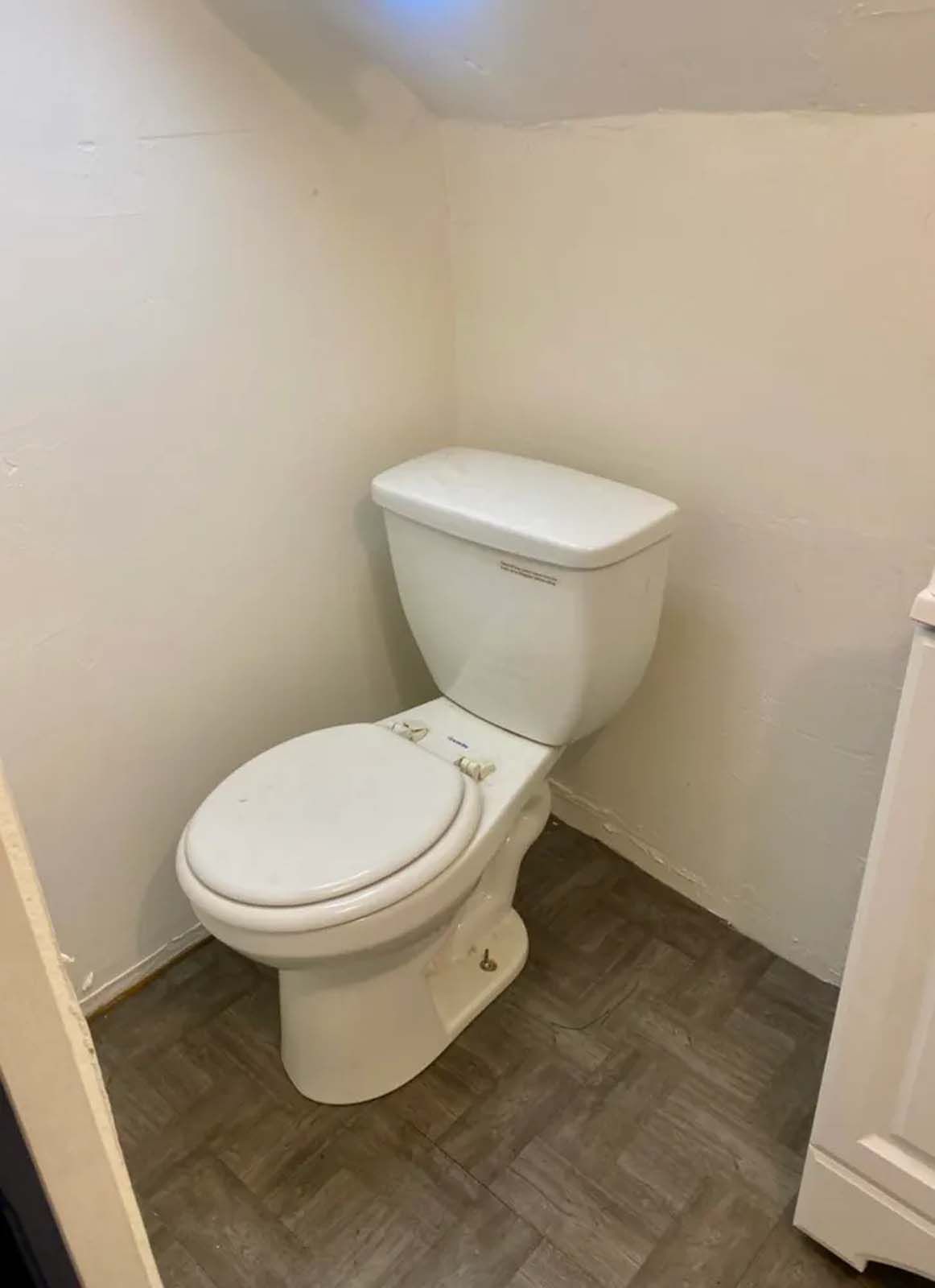 A white toilet is sitting in a small bathroom next to a stove.