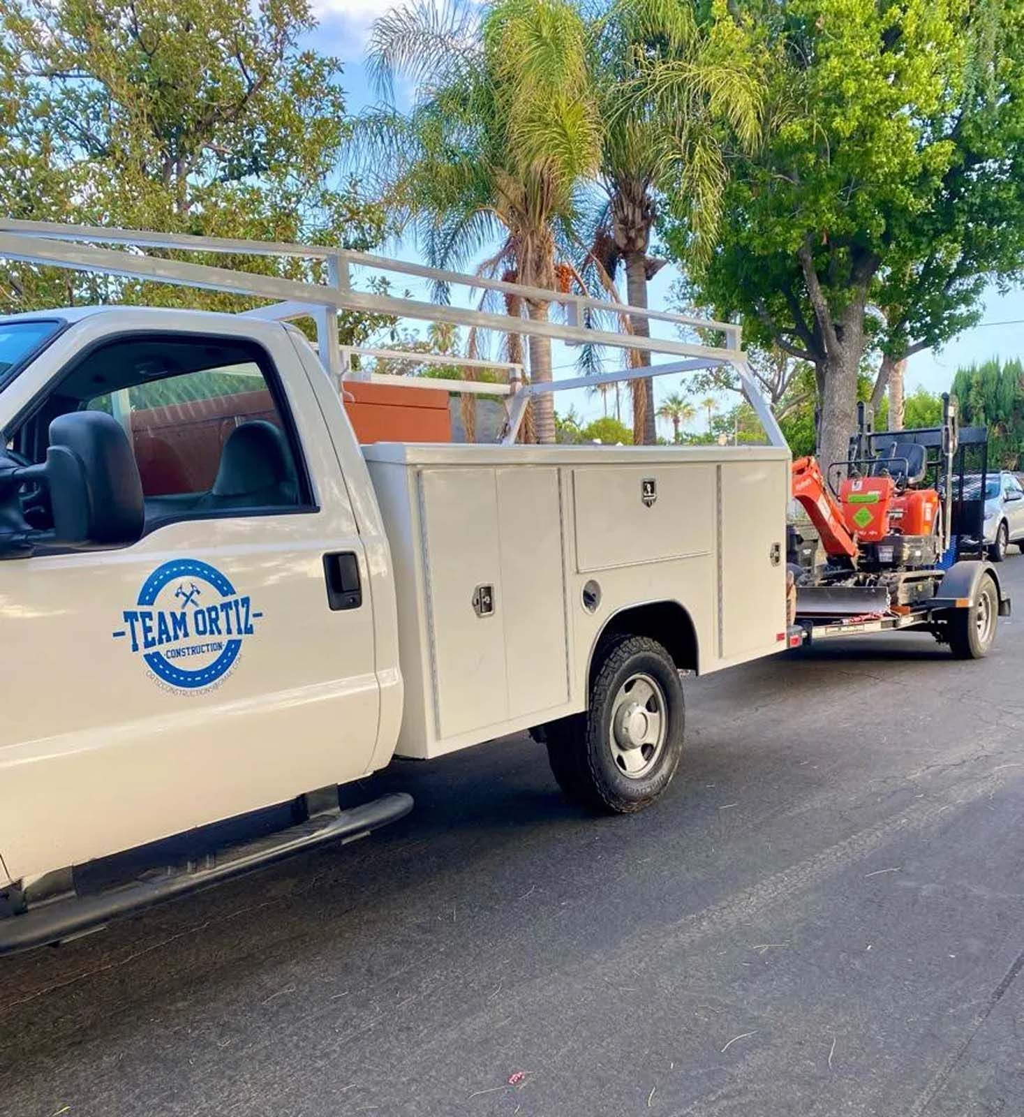 A white truck with a trailer attached to it is parked on the side of the road.